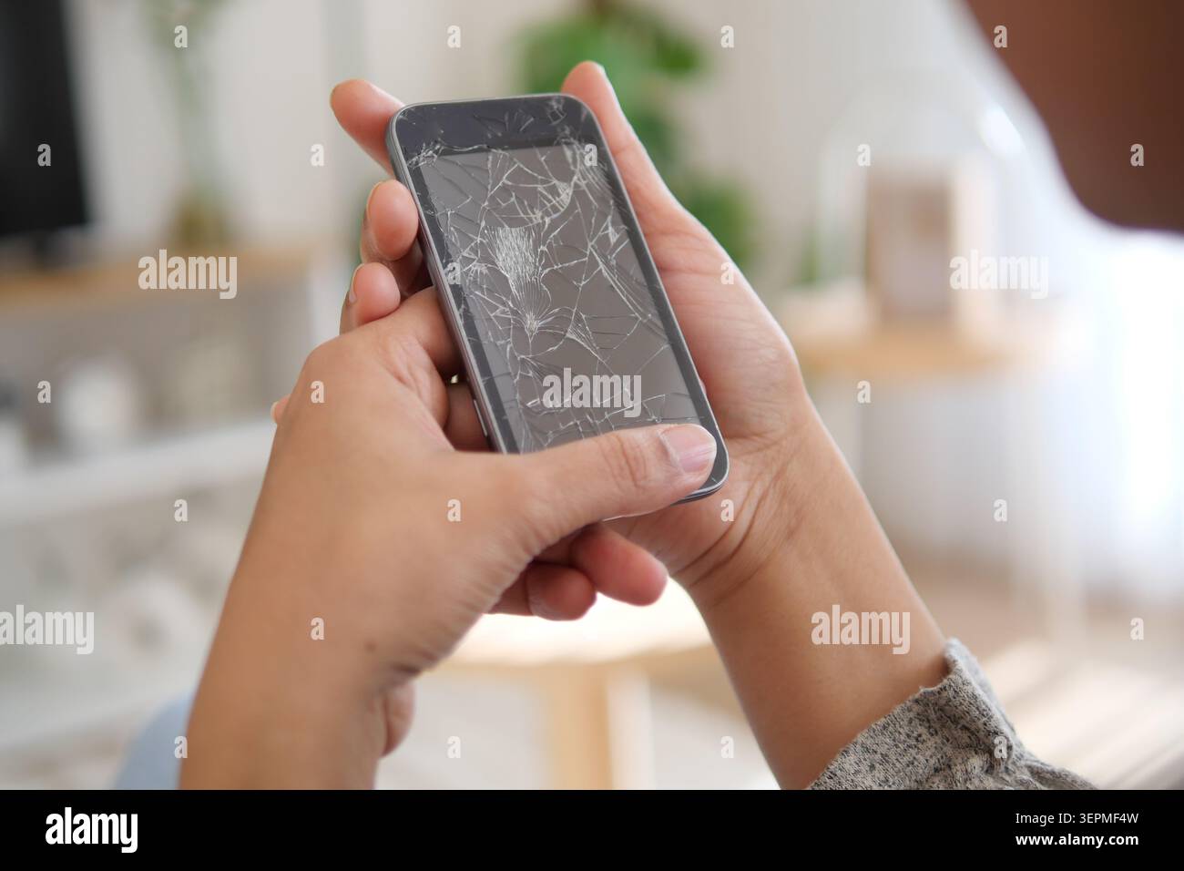 Der Bildschirm des Telefons hat Risse und eine Person hält ihn in der Hand Stockfoto