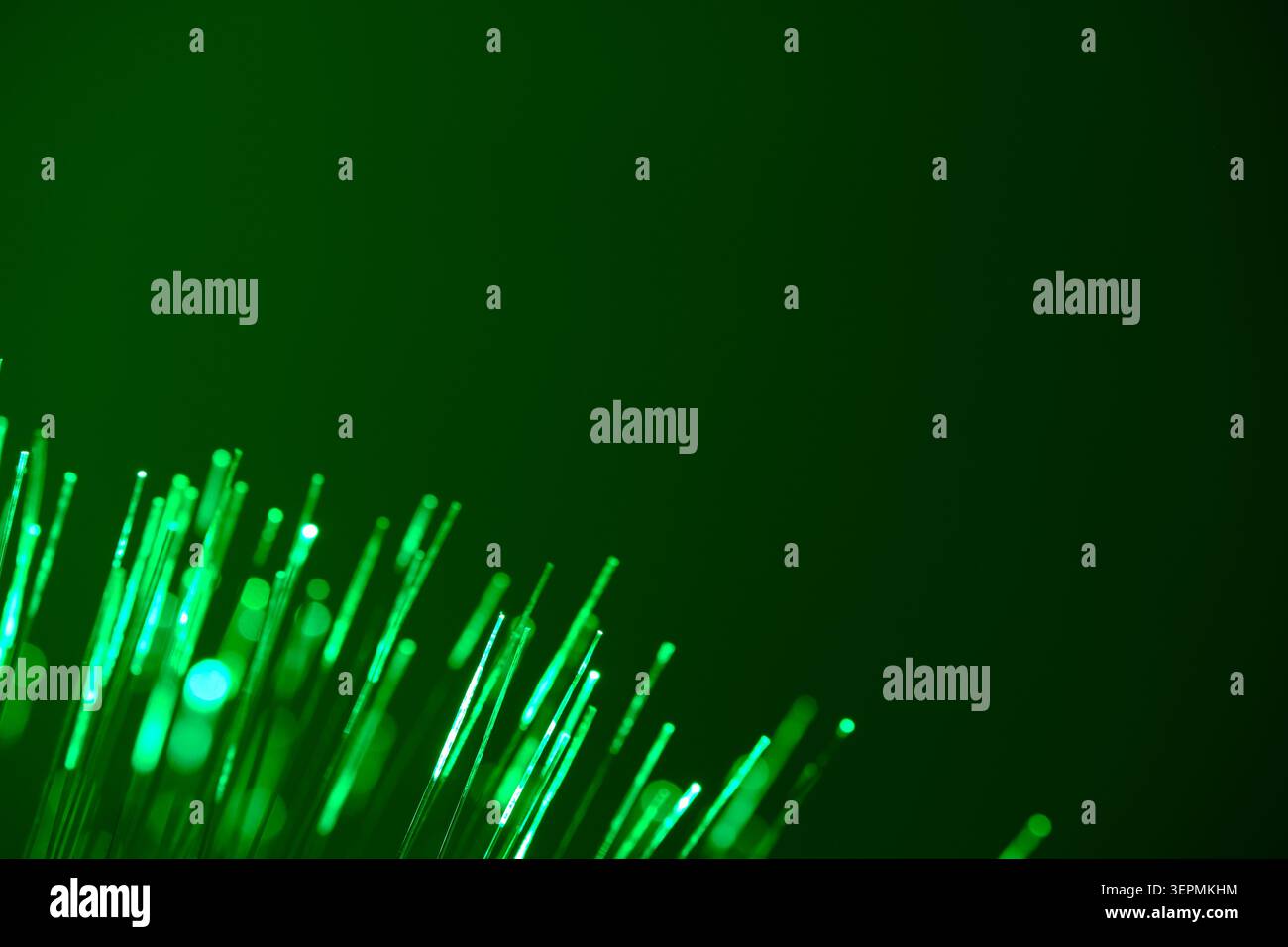 Grüne Glasfaserfäden, die diagonal im dunklen Eckrahmen leuchten Stockfoto