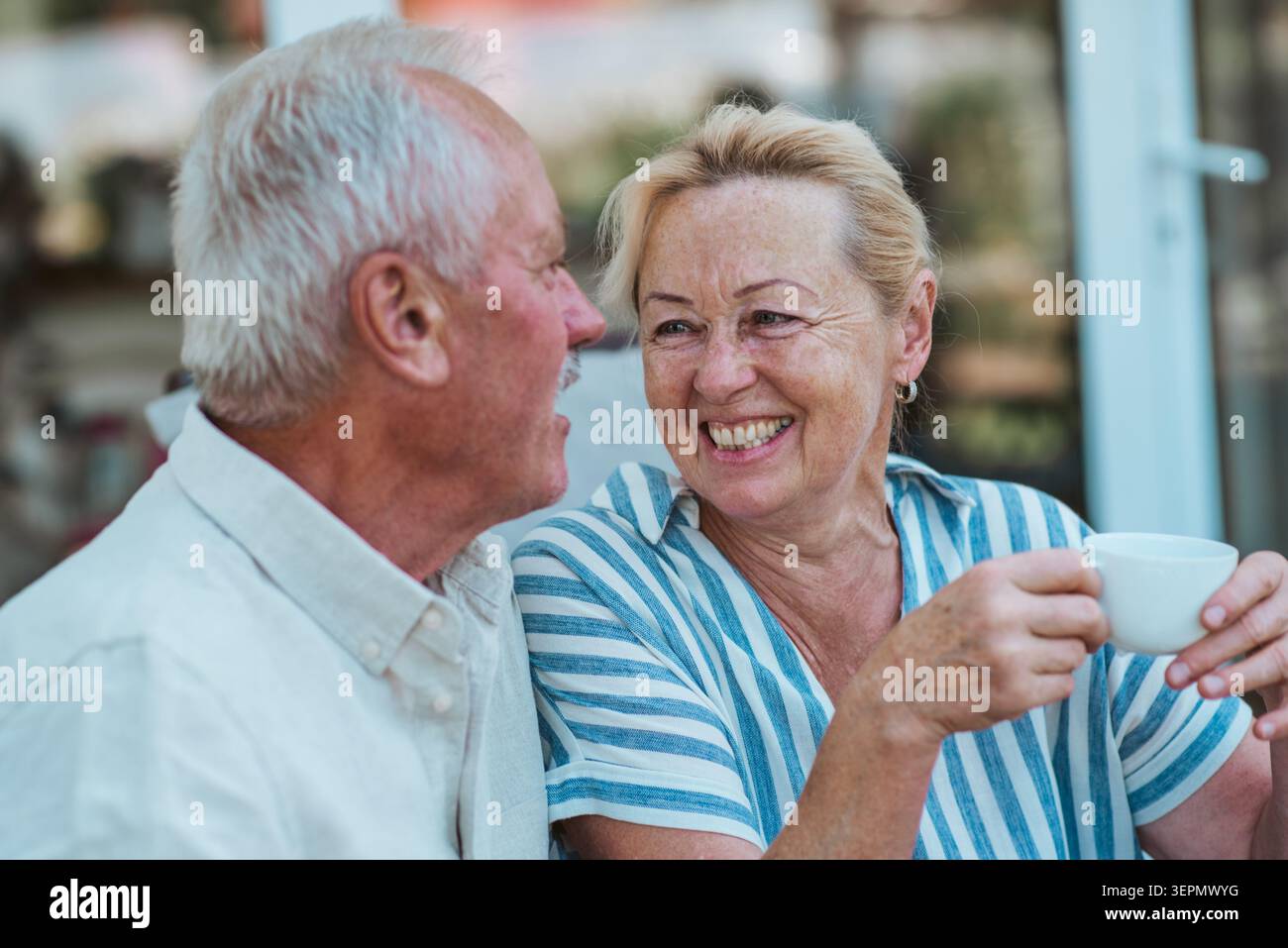 Lächelndes älteres Paar, das im Garten Kaffee genießt. Stockfoto