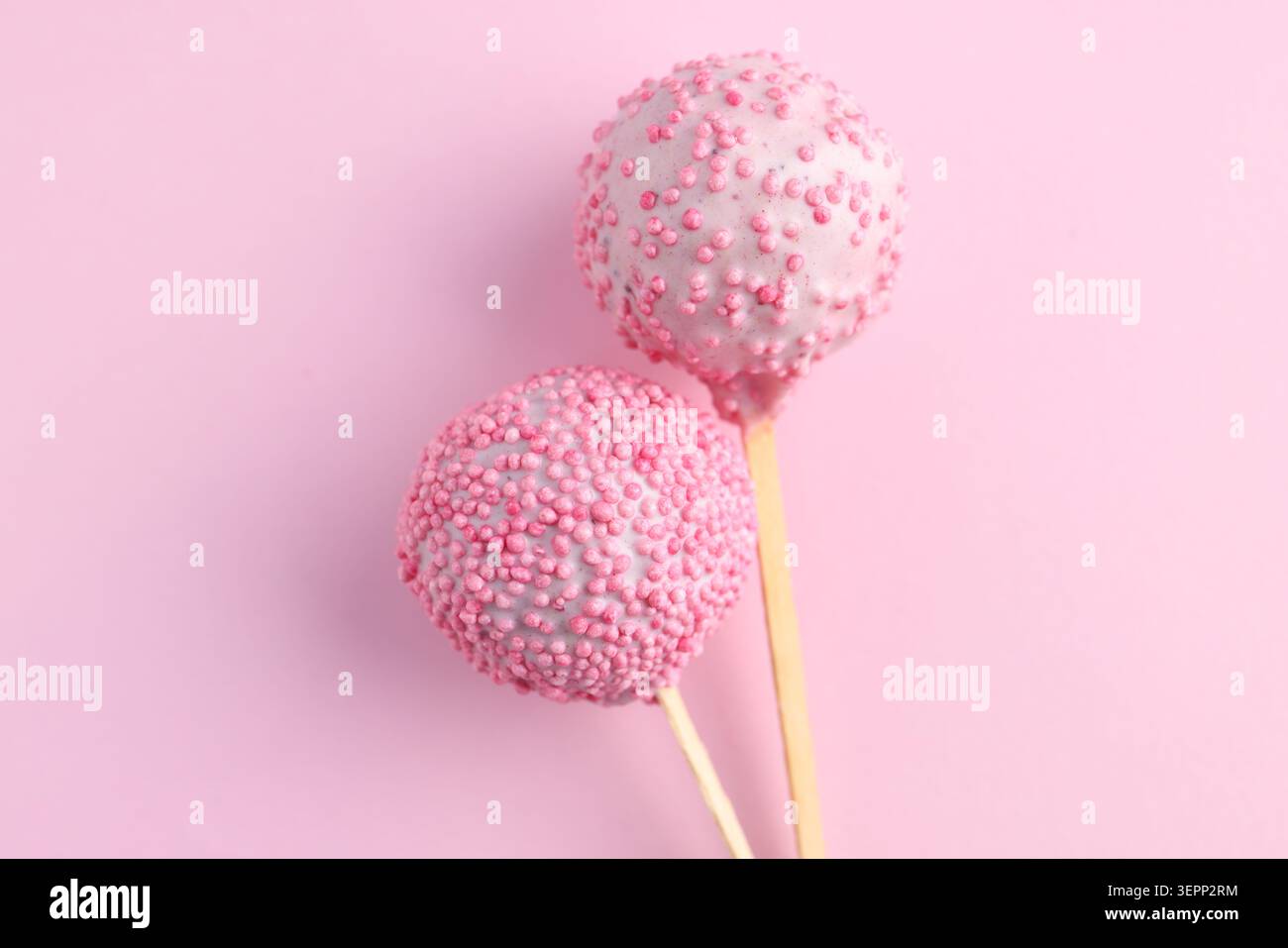 Zwei leckere Kuchen-Pops mit Streuseln auf rosa Hintergrund, Draufsicht Stockfoto