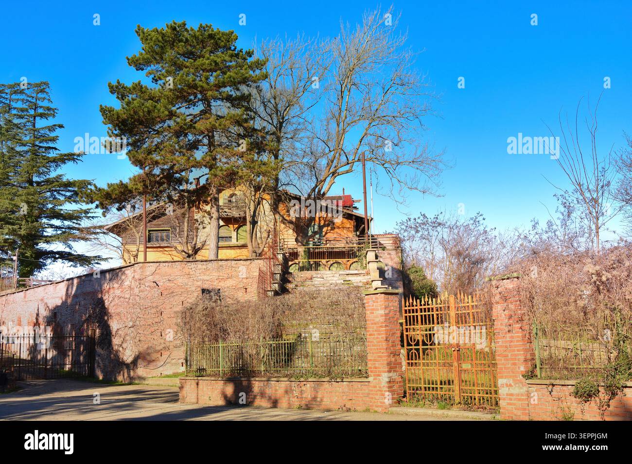 Ein eindringliches Foto einer verlassenen Villa mit verwitterten Wänden, kaputten Fenstern und einer ruhigen, überwachsenen Atmosphäre. Stockfoto