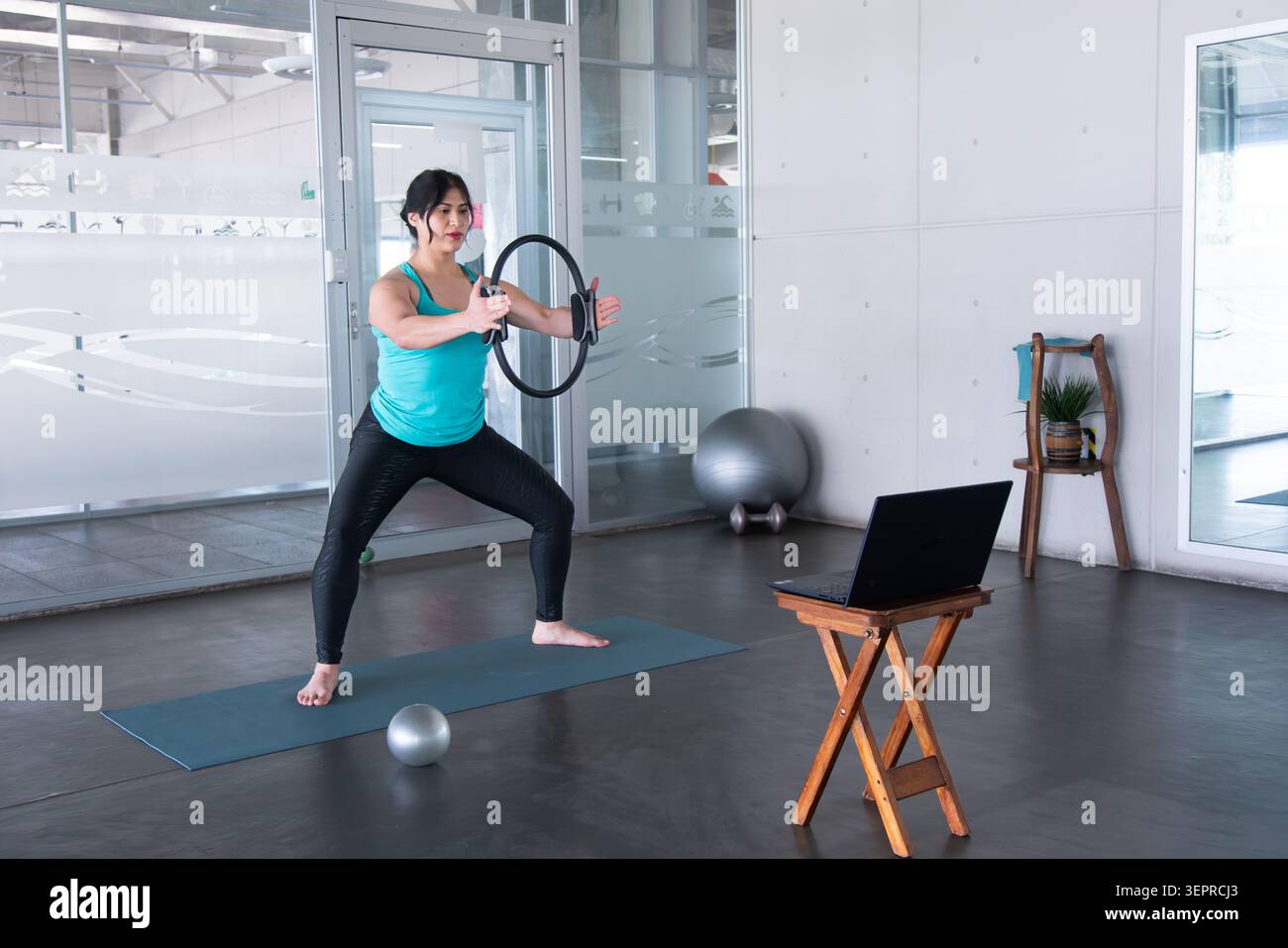 Frau, die Pilates mit Widerstandsring nach Online-Kurs trainiert Stockfoto