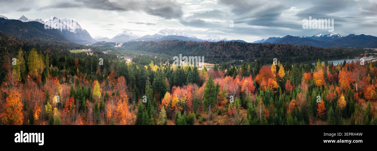 Farbenfroher, malerischer Herbstwald mit wunderschönem bewölktem Himmel und Bergen im Hintergrund, Panoramablick auf die Landschaft aus der Luft Stockfoto