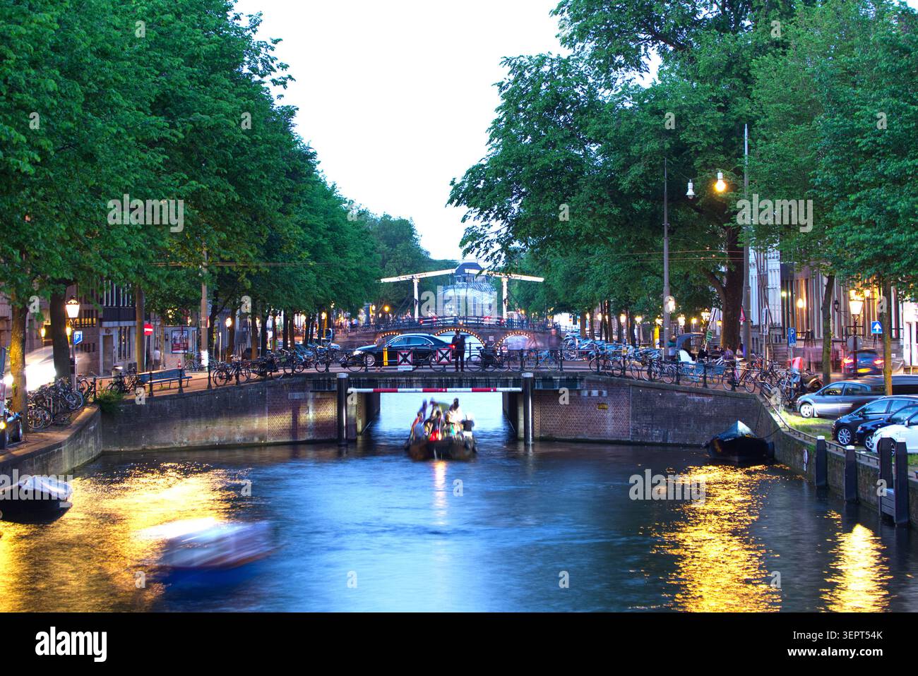Amsterdamer Kanal in der Abenddämmerung am Sommertag. Eine längere Belichtungszeit erzeugt sanfte atmosphärische Reflexionen im Wasser mit sanfter Beleuchtung. Stockfoto