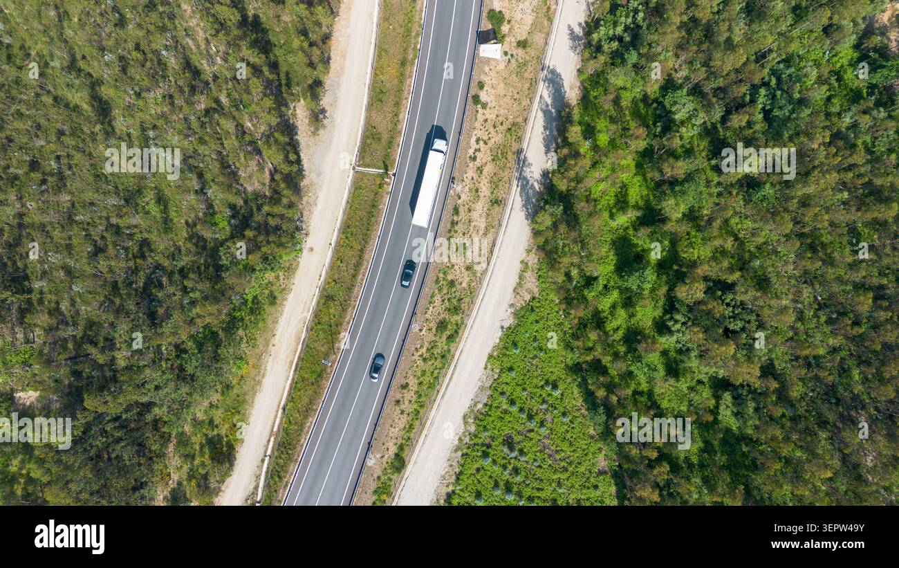 Autobahnverkehr einschließlich Lkw und Autos, die durch eine üppige grüne ländliche Landschaft fahren Stockfoto