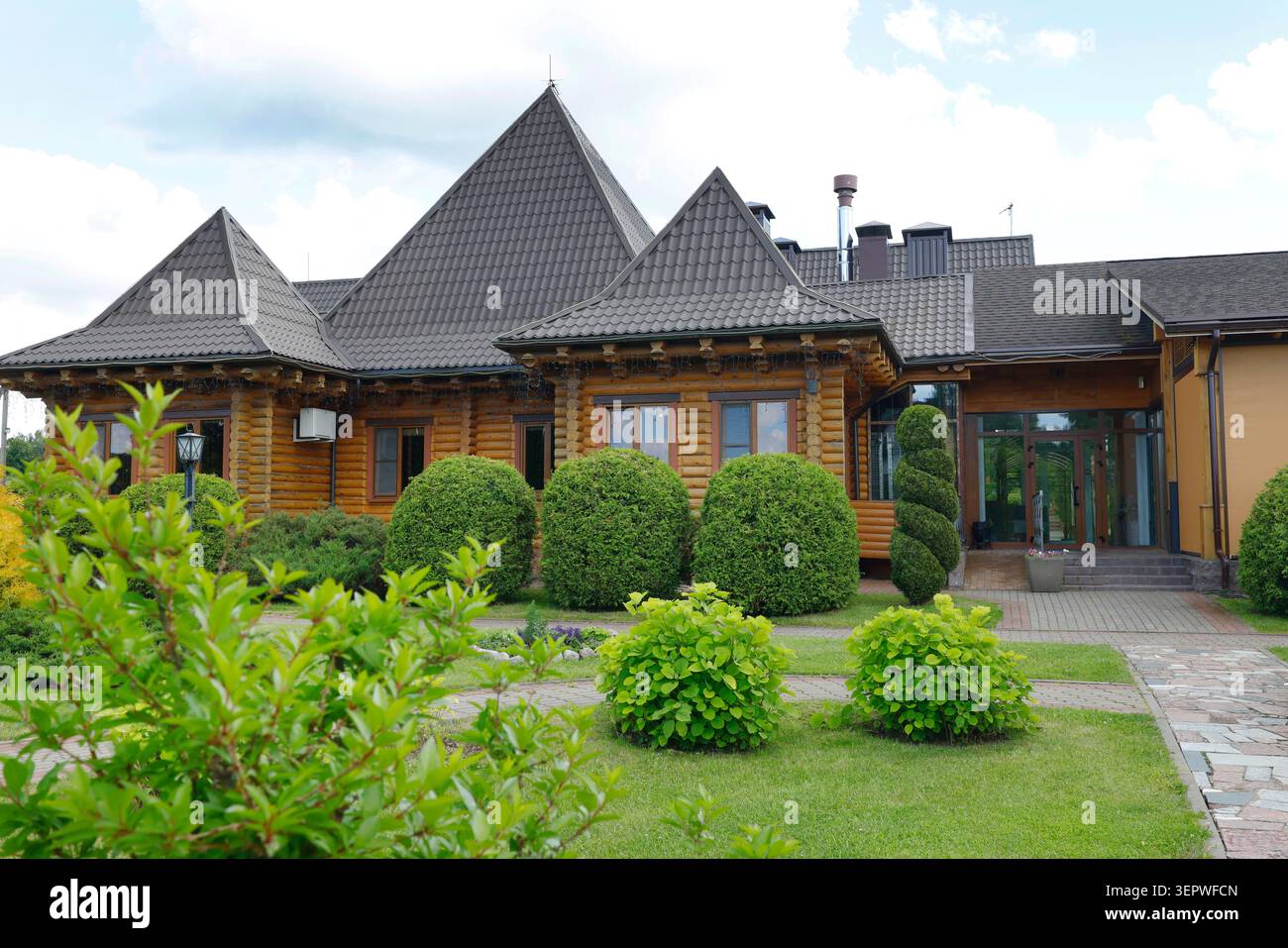 Luxuriöser hölzerner Landkomplex mit schönem Landschaftsgarten und grünem Rasen. Innenhof Hinterhof eines modernen Geschäftsgebäudes mit Steinweg und Stockfoto