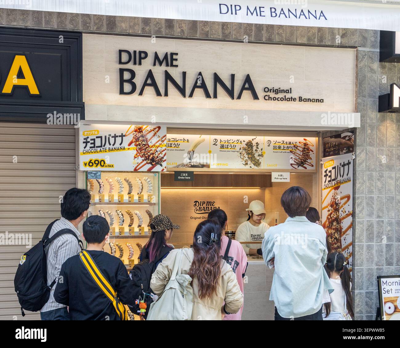 Menschenmenge bestellt maßgeschneiderte Schokoladenbananen von DIP ME BANANA auf der Takeshita-Straße in Harajuku, Tokio, Japan. Stockfoto