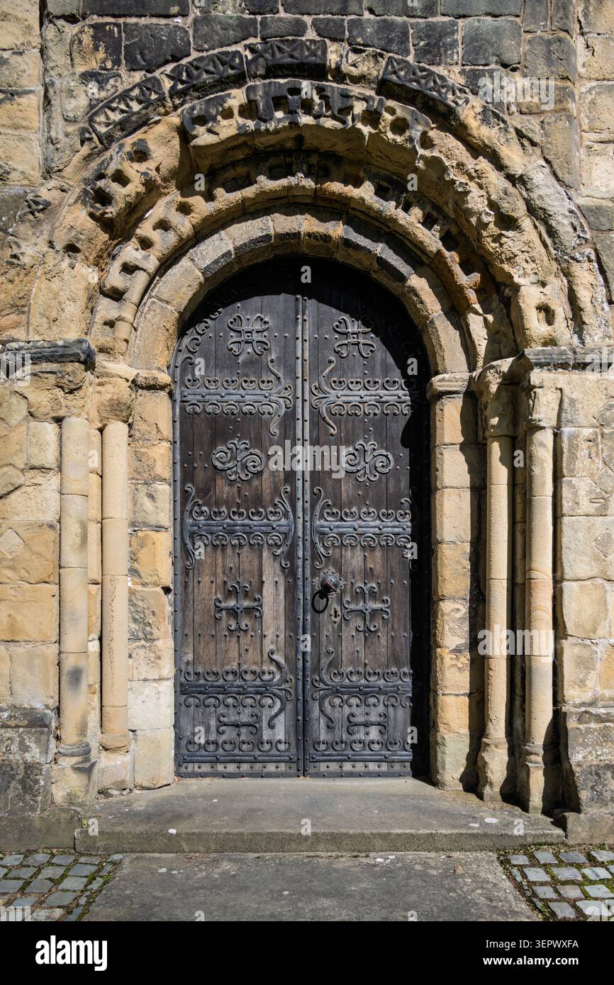 Historische normannische Westtür mit kunstvoll geschnitzten Chevron-Motiven und Mühlenkreuzen in der All Saints Church in Bakewell, Derbyshire Stockfoto