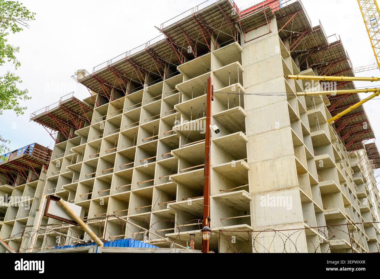 Baustelle eines Wohnkomplexes aus Beton mit unvollendeter Struktur und einem Turmkran. Tagsüber. Konzept des effizienten Ingenieurprojektmannes Stockfoto