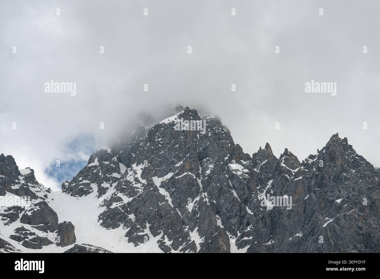 Majestätische felsige Berggipfel verschwinden in dramatischen Sturmwolken. Malerische alpine Hochlandlandschaft mit epischen Berggipfeln im Nebel. Stockfoto