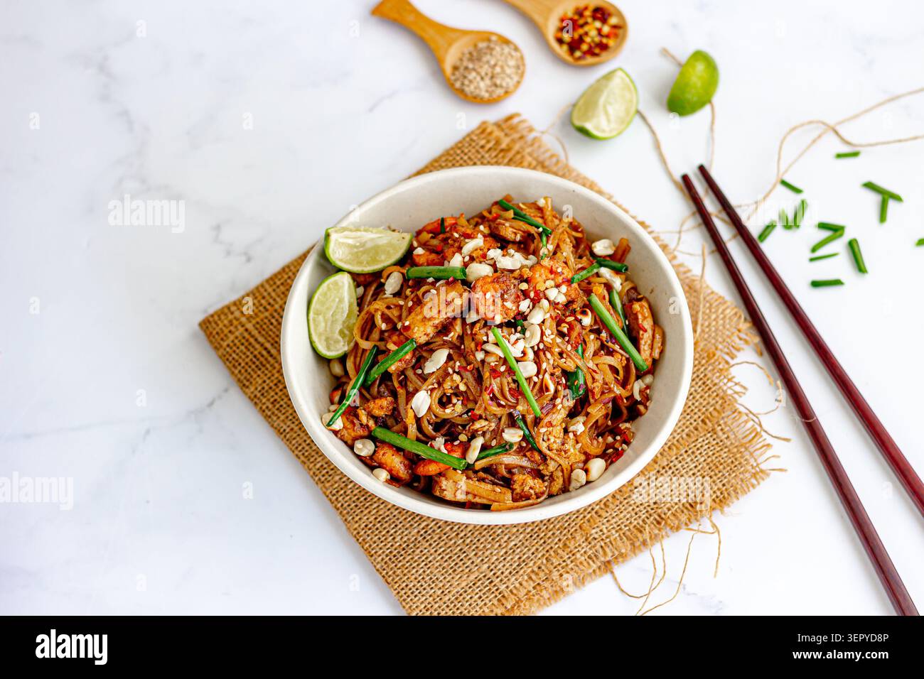 Pad Thai Nudeln mit Garnelen, Tofu und Limette in der Schüssel auf weißem Marmorhintergrund mit Kopierraum Stockfoto