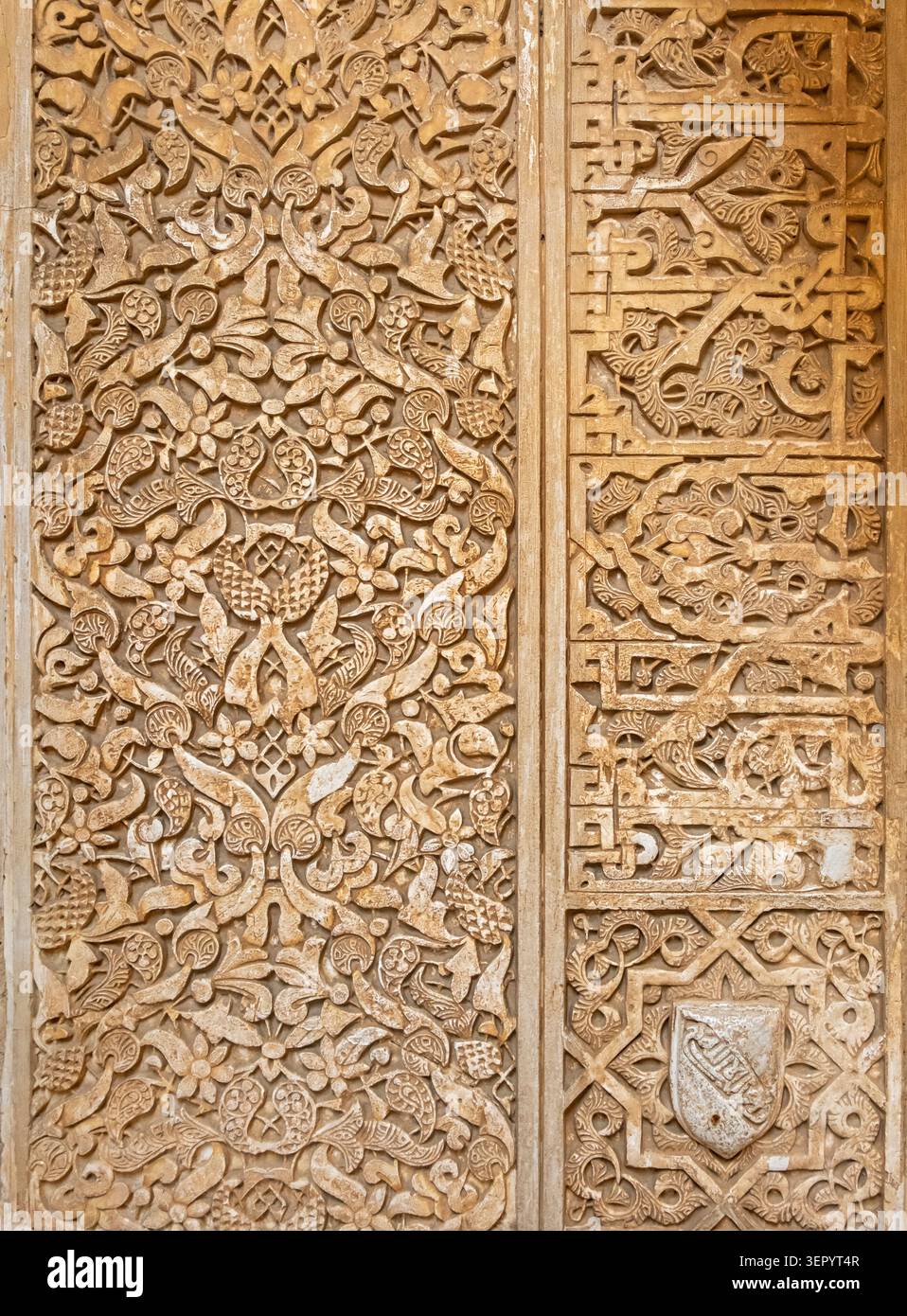 Eine detaillierte Ansicht von geschnitzten arabesken Blumenmustern und arabischer Kalligraphie-Schrift auf einer Gipswand in der Alhambra in Granada, Spanien Stockfoto