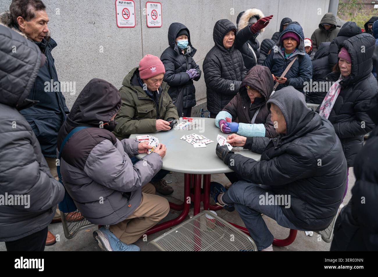 13.12.2025, USA, Massachusetts, Boston - Eine Gruppe chinesischer Einwanderer sitzt an einem kalten Wintertag in Chinatown um einen Tisch und spielt Karten. 0SL251213D Stockfoto