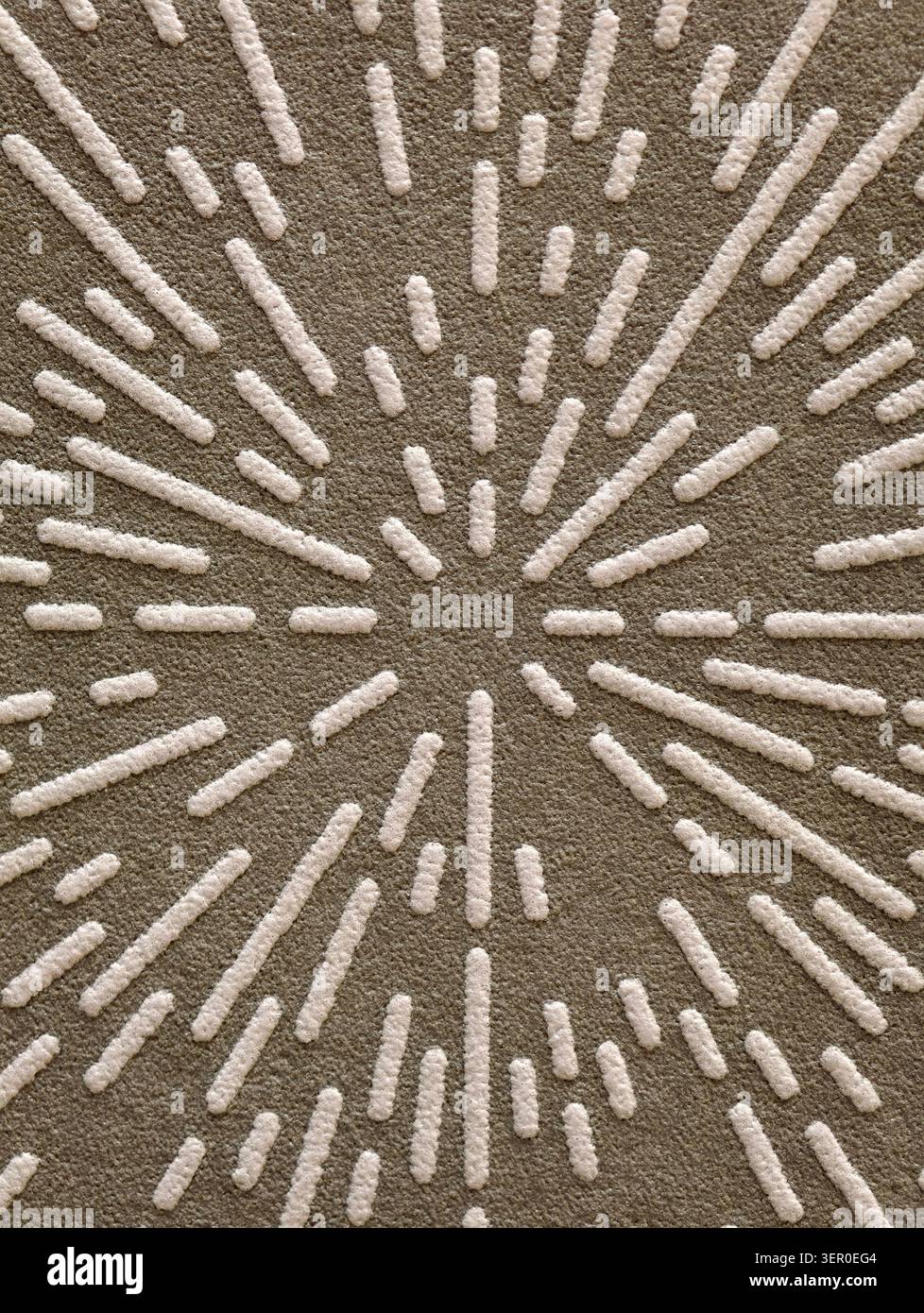Blick von oben auf einen beigefarbenen texturierten Teppich mit einem radialen Burst-Muster aus erhöhten getufteten Linien. Der Teppich zeigt einen dichten, geschwungenen Stapelhintergrund mit Fortsetzung Stockfoto