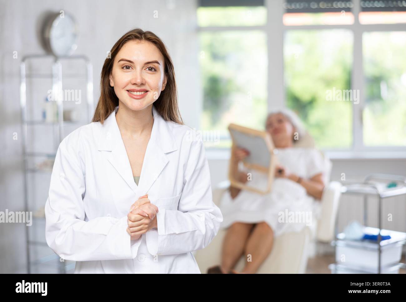 Weibliche Ärztin Kosmetikerin steht mit einer Frau, die in der Arztpraxis nach hinten schaut. Stockfoto