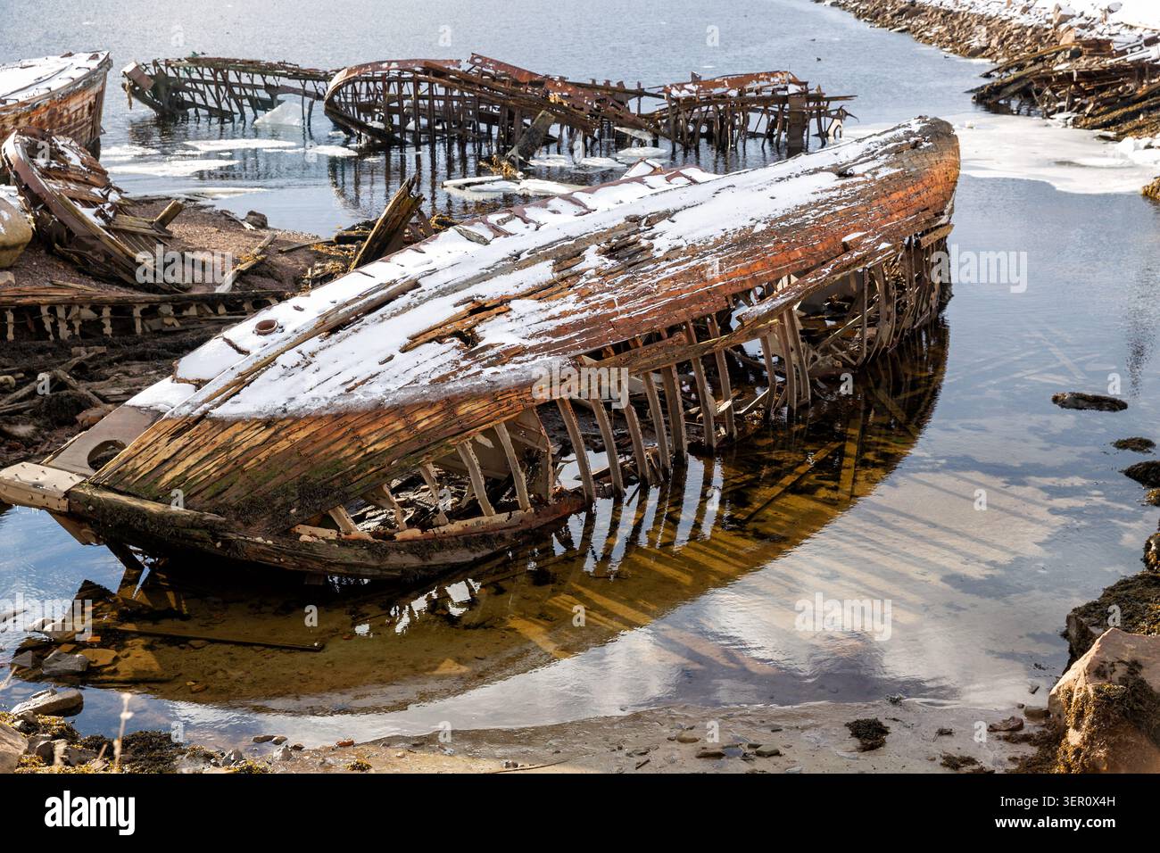 Friedhof alter Boote am Ufer der Barentssee in Teriberka bei Ebbe. Region Murmansk, Russland Stockfoto