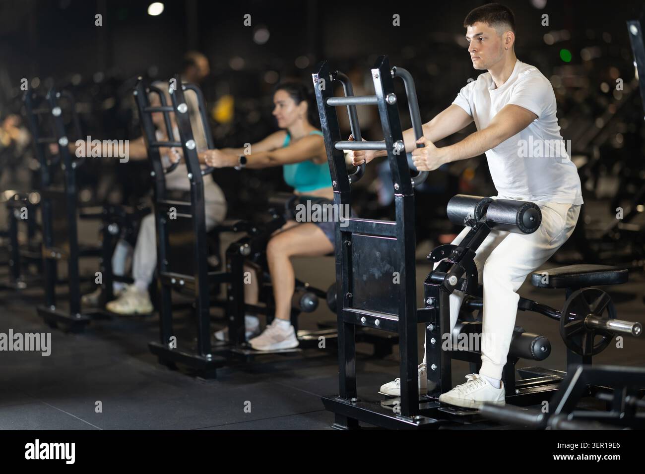 Ein Typ, der im Fitnessstudio auf dem Gerät sitzende Widerstandsübungen durchführt Stockfoto