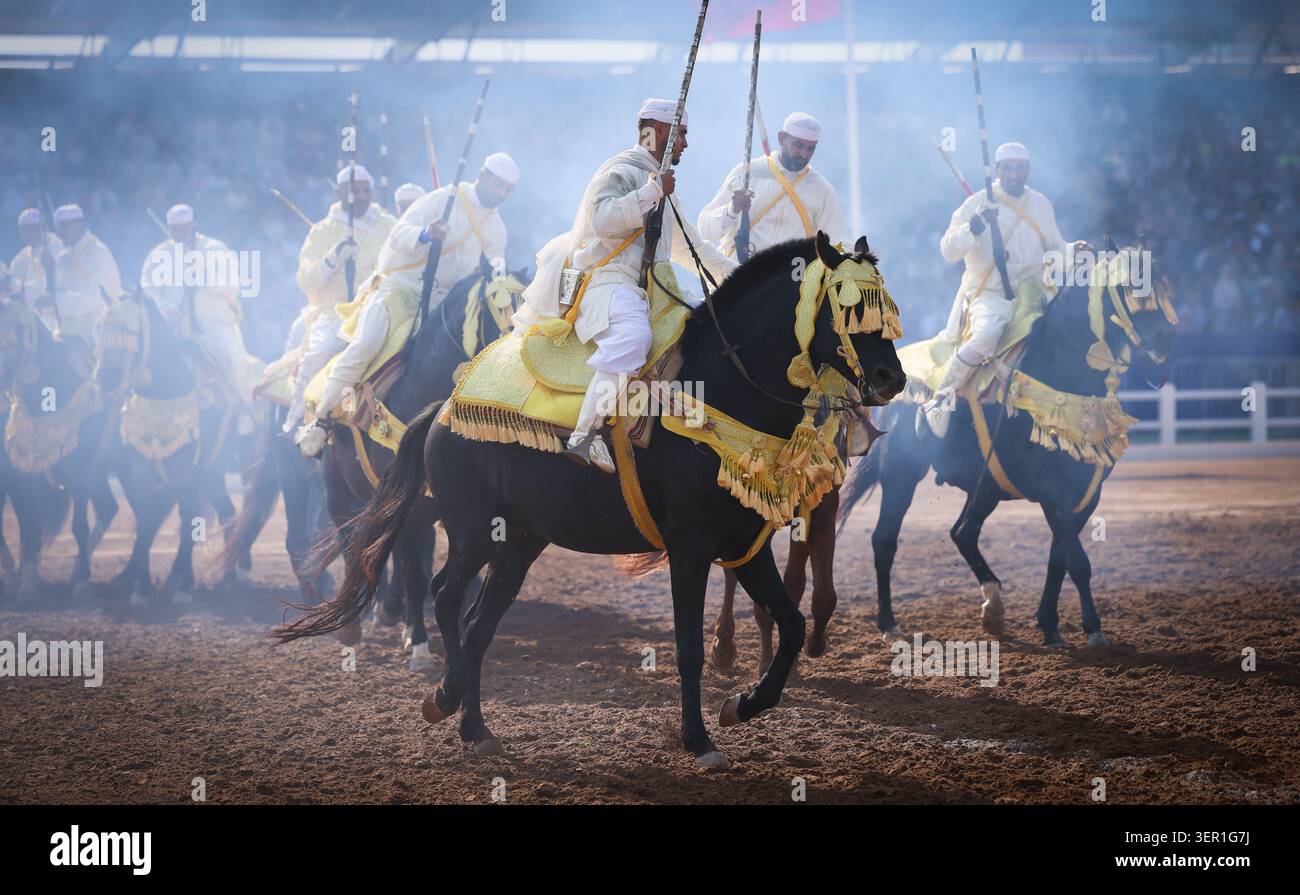 Tbourida, Eine dramatische Szene marokkanischer Fantasien, entfaltet sich, während Reiter durch Staub und Rauch galoppieren und Kraft, Eleganz und Tradition vermischen. Marokko Stockfoto