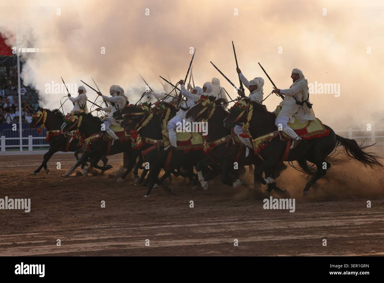 Tbourida, Eine dramatische Szene marokkanischer Fantasien, entfaltet sich, während Reiter durch Staub und Rauch galoppieren und Kraft, Eleganz und Tradition vermischen. Marokko Stockfoto