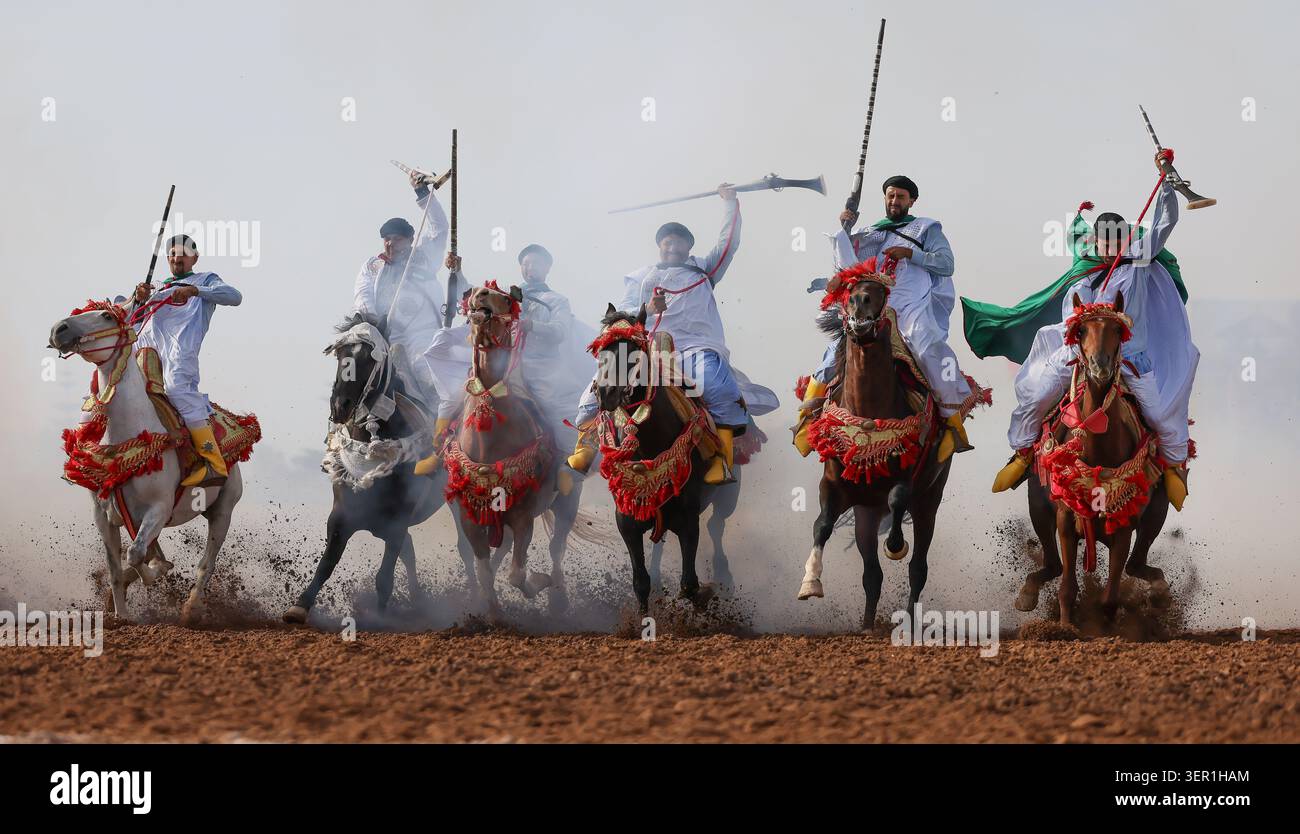Tbourida, Eine dramatische Szene marokkanischer Fantasien, entfaltet sich, während Reiter durch Staub und Rauch galoppieren und Kraft, Eleganz und Tradition vermischen. Marokko Stockfoto