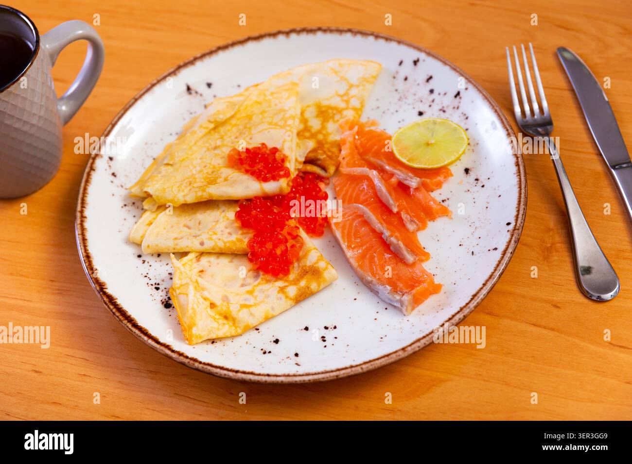 Dünne Pfannkuchen mit Kaviar und Lachs auf einem Teller Stockfoto