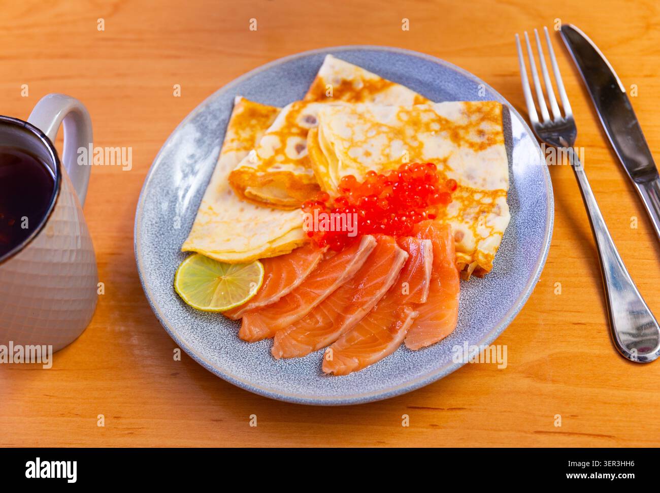 Dünne Pfannkuchen mit Kaviar und Lachs auf einem Teller Stockfoto