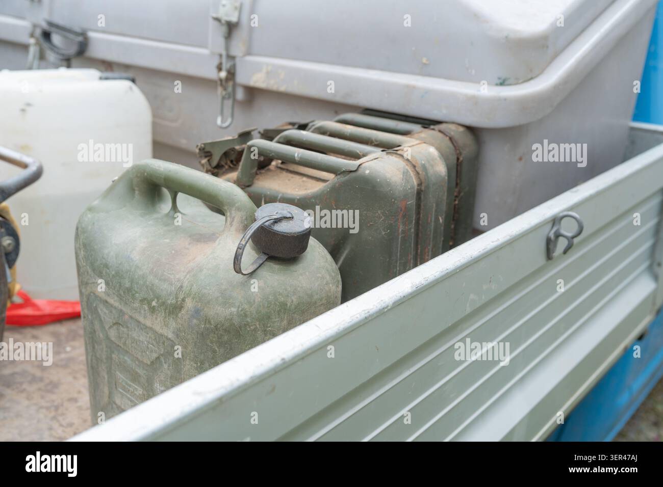 Kraftstoffkanister aus Kunststoff und industrielle kanister, die in einem offenen Transportbehälter aus Aluminium-Lkw-Transportbett zur Betankung vor Ort gesichert sind. Nahaufnahme von Grün und Stockfoto