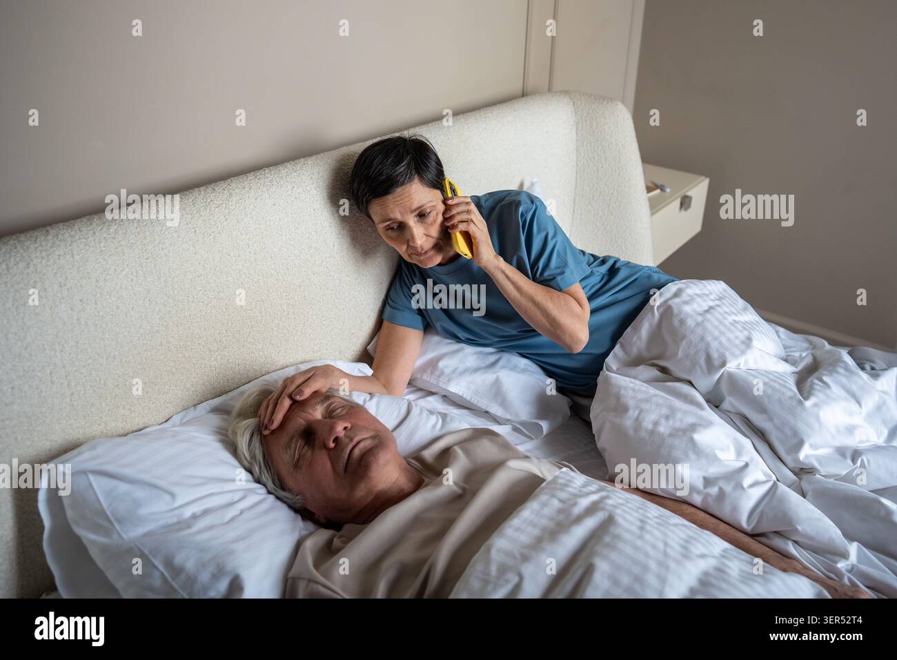 Belastete Frau messen Fieber, während Arzt für kranken älteren Ehemann im Bett, häusliche Gesundheitspflege rufen Stockfoto