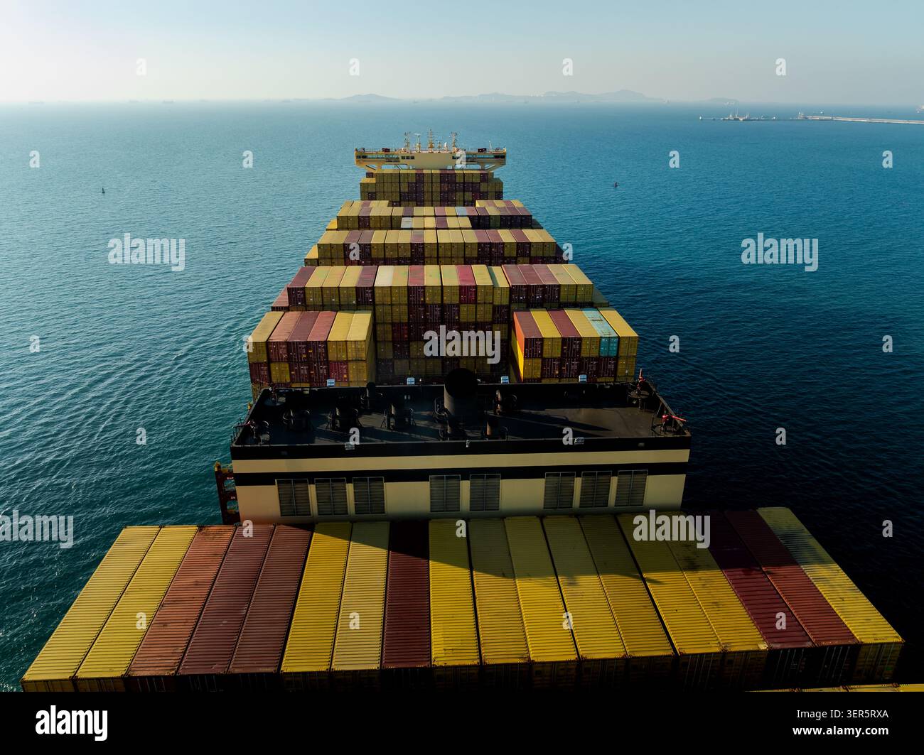 Ein Blick aus einem hohen Winkel über gestapelte Frachtcontainer auf einem Handelsschiff, das auf der offenen See in der Nähe des Hafens laem chabang chonburi thailand navigiert. Stockfoto