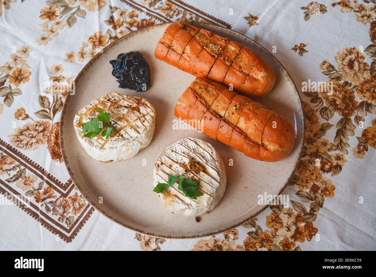 Gebackener Camembert mit Kräuter-Baguette und Heidelbeermarmelade Stockfoto
