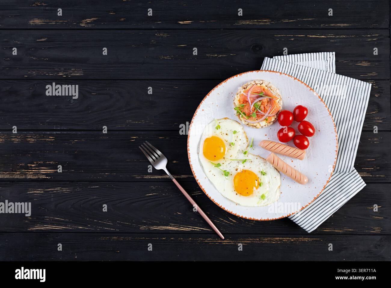 Spiegeleier mit Wurst, Kirschtomaten und Buchweizenbrot mit Lachsfisch Stockfoto