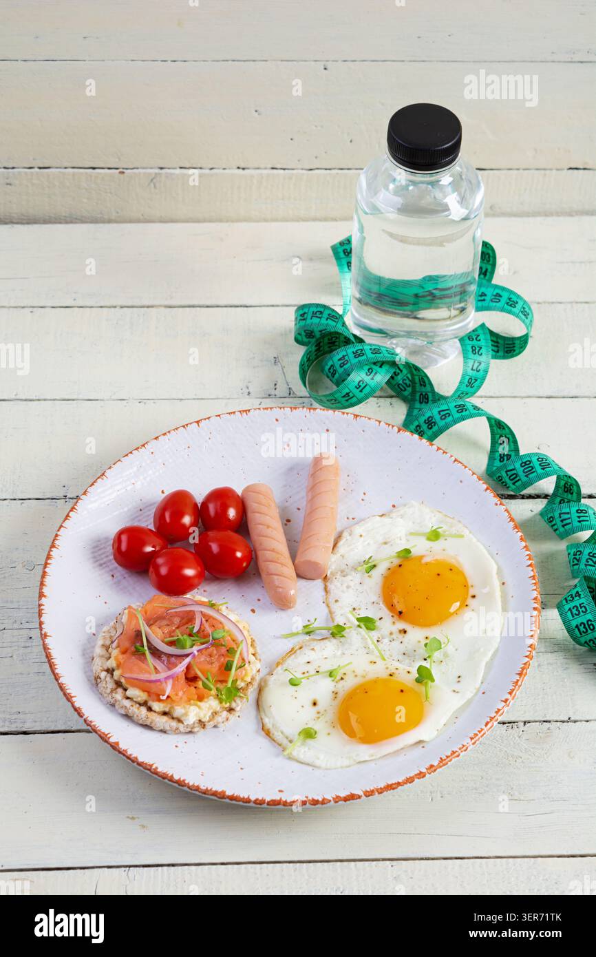 Spiegeleier mit Wurst, Kirschtomaten und Buchweizenbrot mit Lachsfisch Stockfoto
