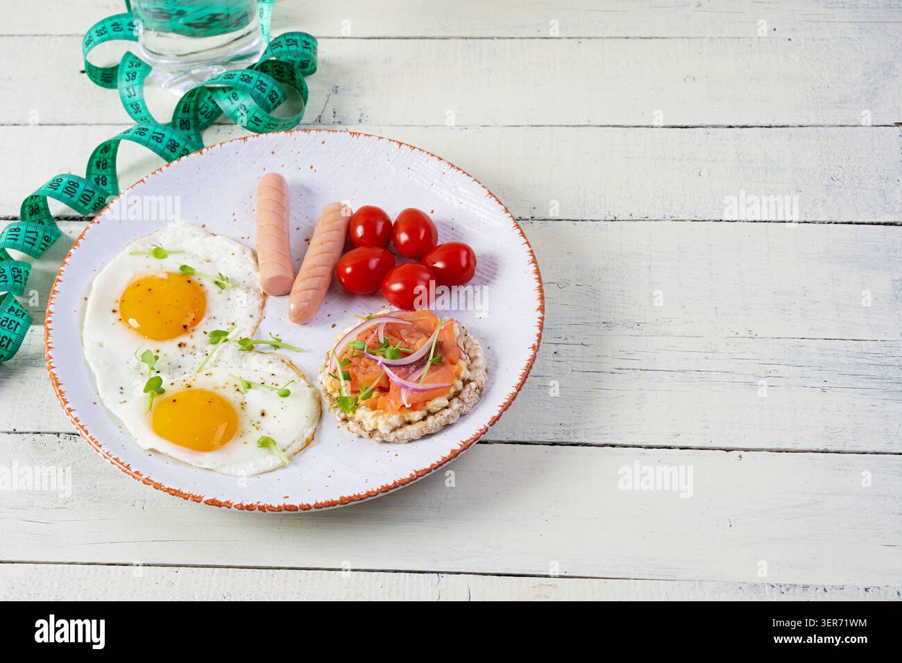 Spiegeleier mit Wurst, Kirschtomaten und Buchweizenbrot mit Lachsfisch Stockfoto