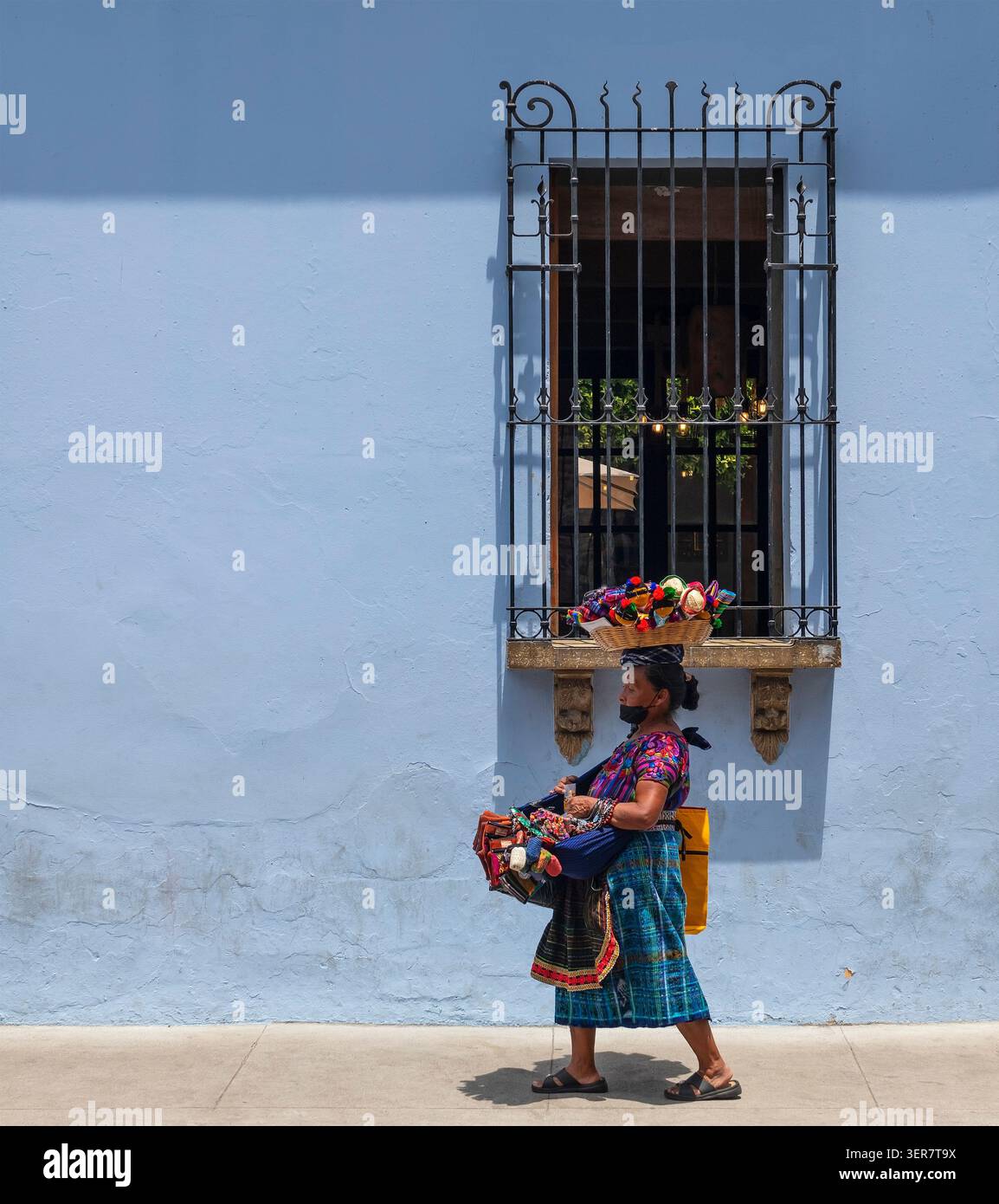 Guatemaltekische Maya-Verkäuferin mit Kunsthandwerk und Fassade im Kolonialstil, Antigua, Guatemala. Stockfoto