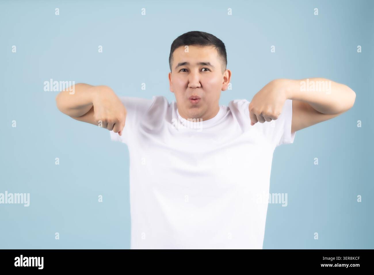 Junger Mann, der mit beiden Zeigefingern nach unten zeigt Stockfoto