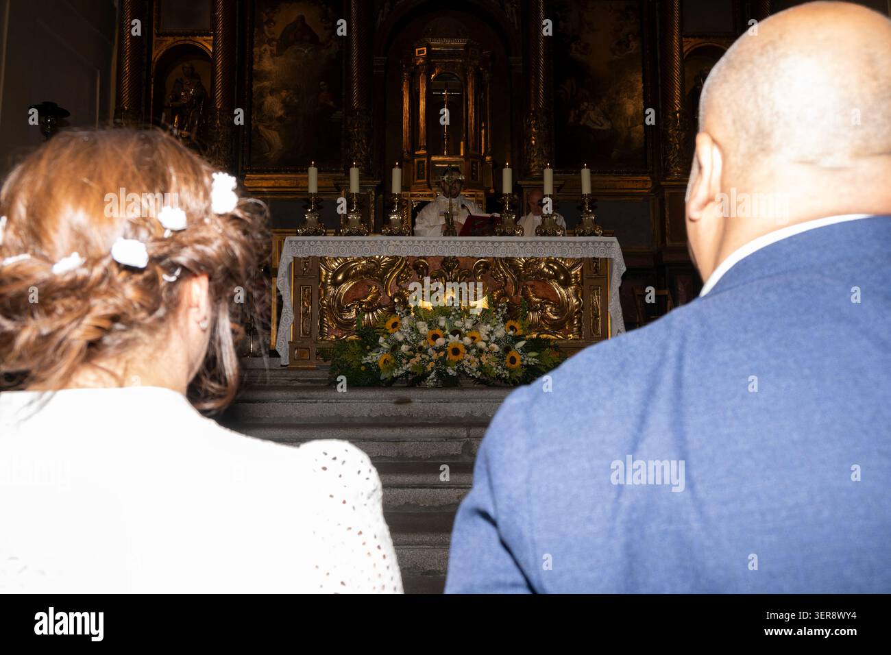 Ein Paar, das an einer Hochzeitszeremonie mit dem Priester an einem geschmückten Altar teilnimmt Stockfoto