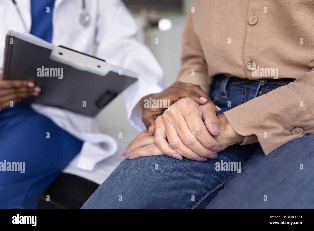 Reife Patientin lernt schlechte Diagnose von junger afrikanischer Ärztin Stockfoto
