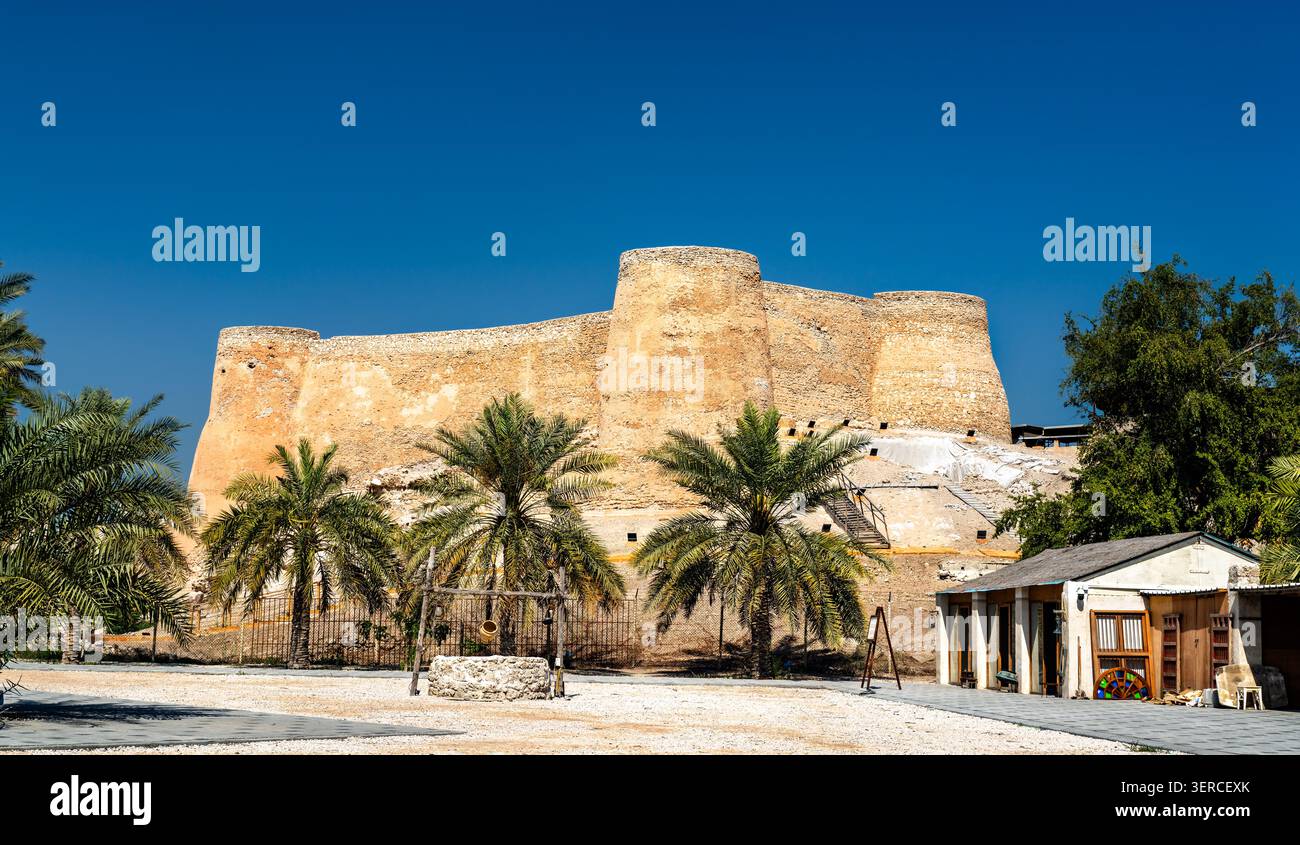 Die alten Steintürme von Tarout Castle umgeben von Palmen unter einem klaren blauen Himmel in Qatif, Saudi-Arabien. Stockfoto