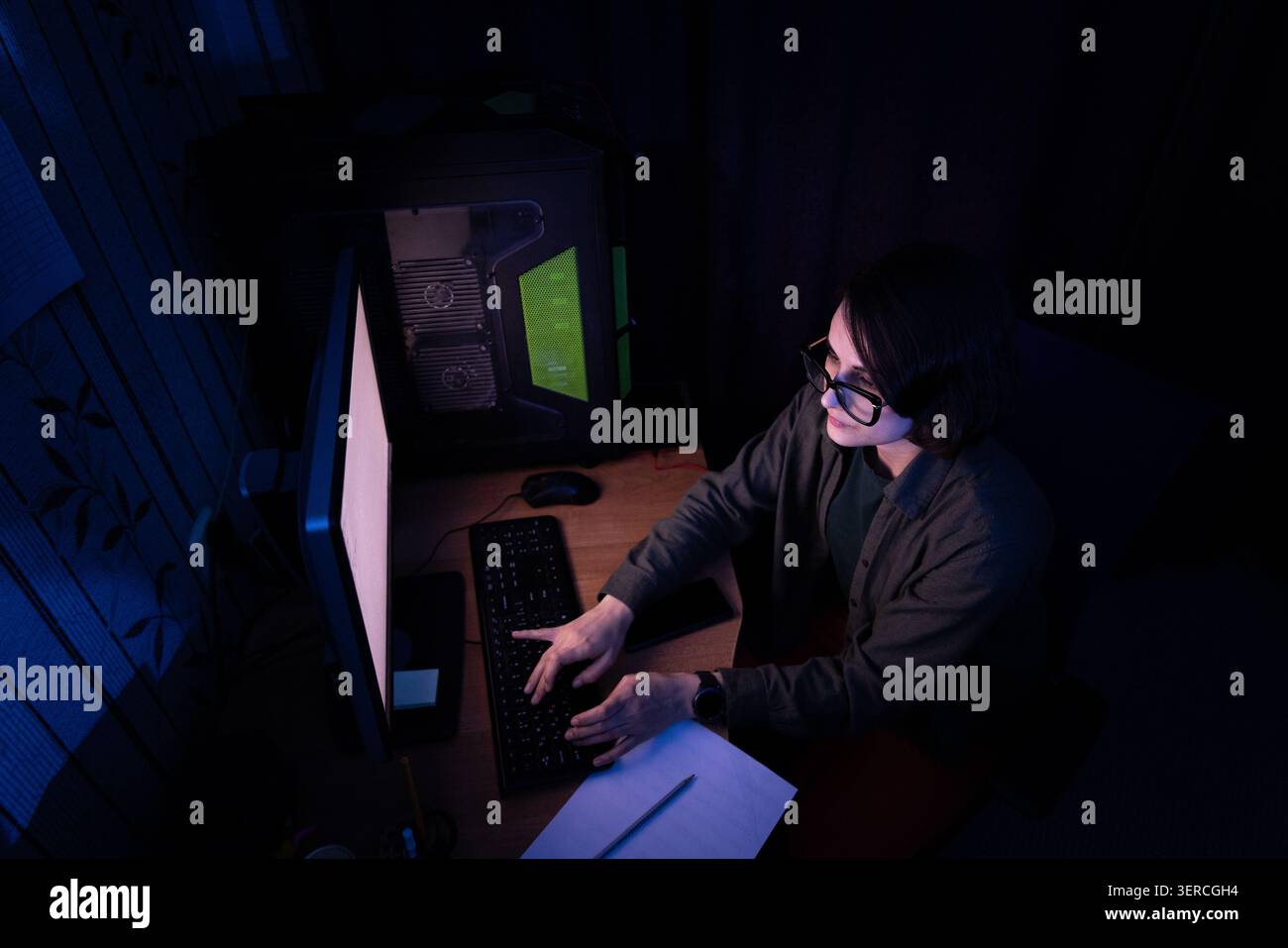 Hochwinkelansicht einer Frau, die nachts auf der Tastatur tippt Stockfoto