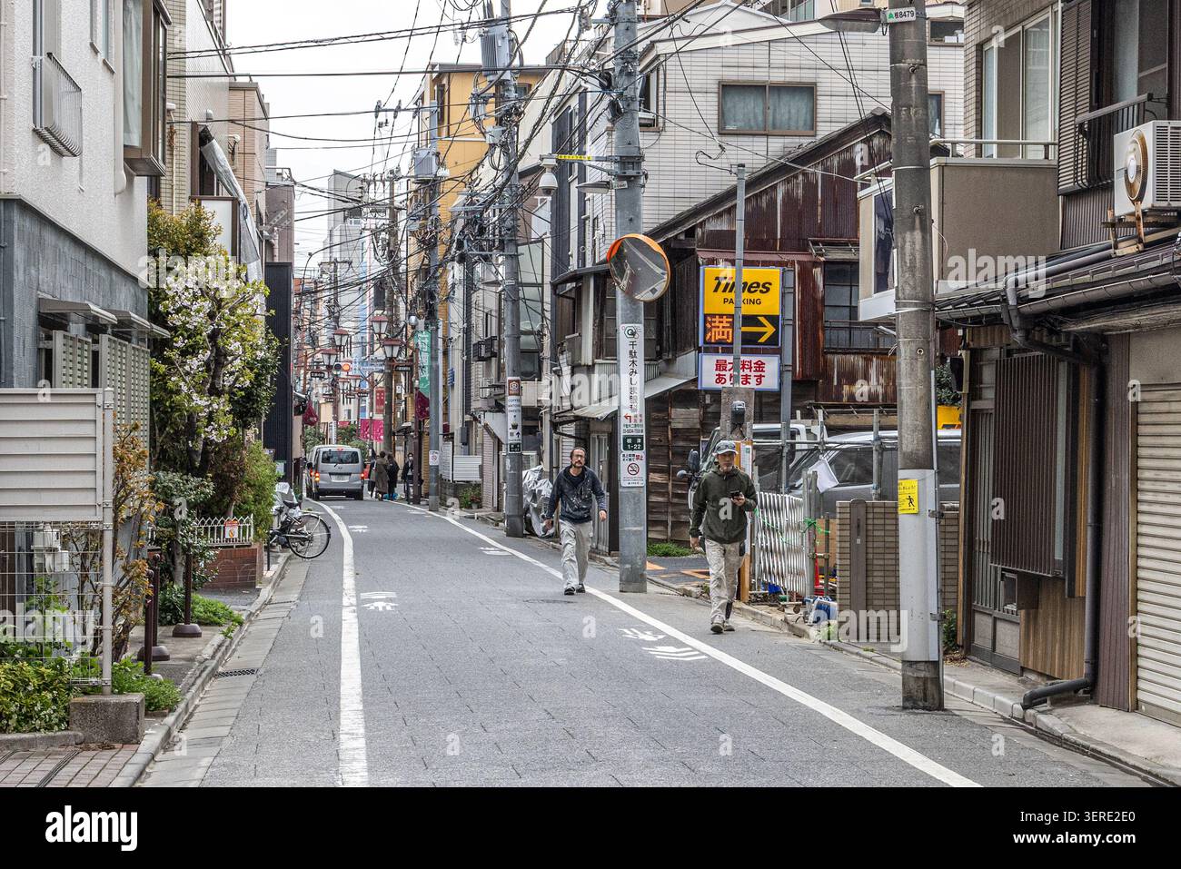 Fußgänger auf einer schmalen gemischten Wohn- und Geschäftsstraße im Yanesen-Viertel im Norden von Tokio, Japan. Stockfoto
