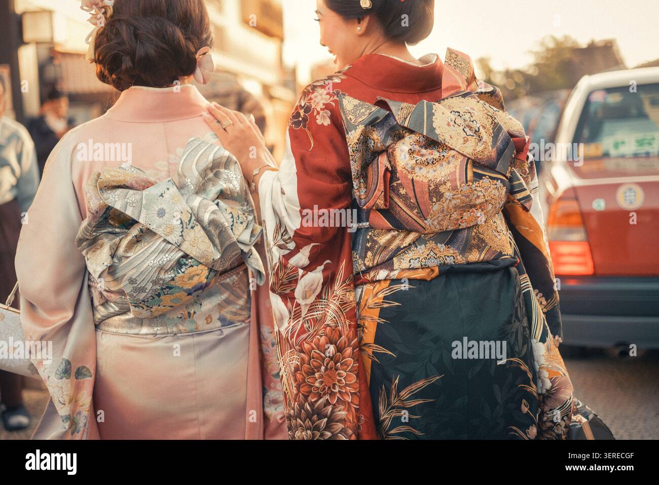 Zwei Kyoto Geiko laufen Seite an Seite durch eine Stadtstraße, entspannt und entspannt, während sie miteinander plaudern. Stockfoto