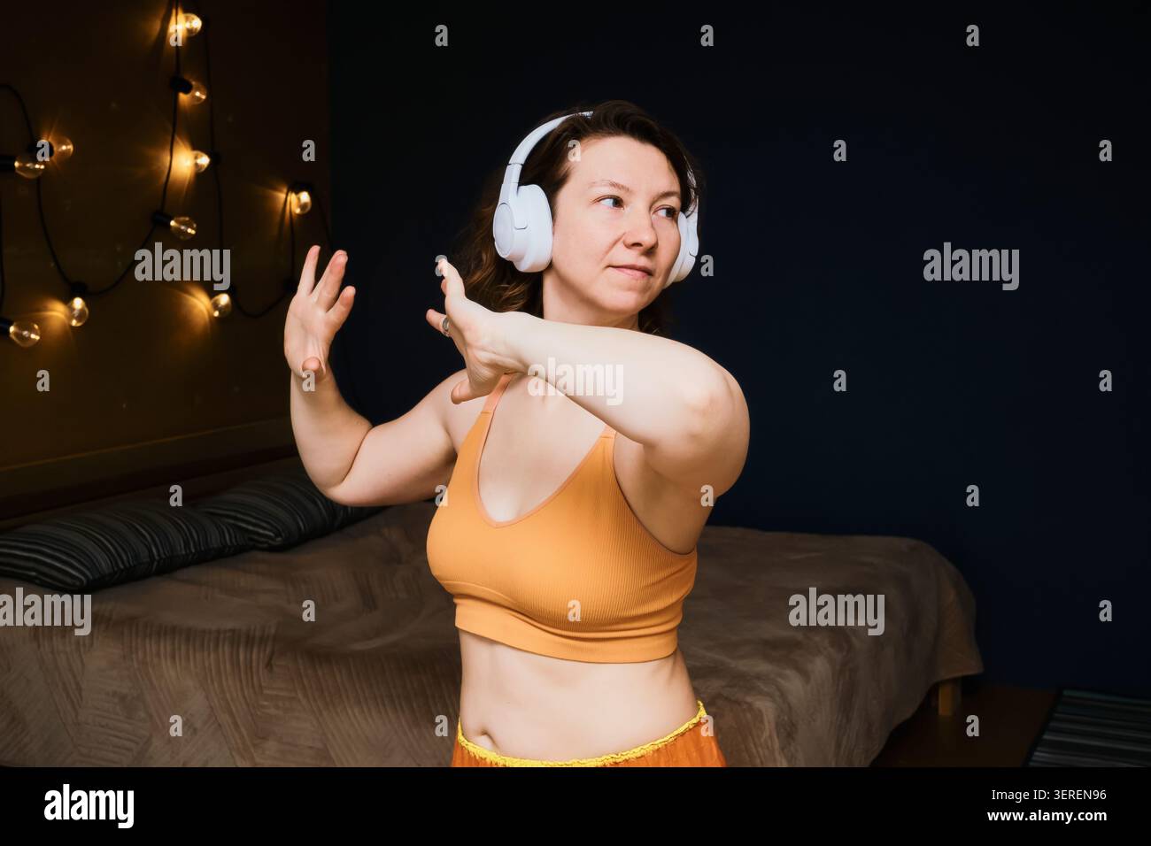 Frau, die Musik mit kabellosen Kopfhörern genießt und ihren Körper in entspannter Atmosphäre bewegt Stockfoto