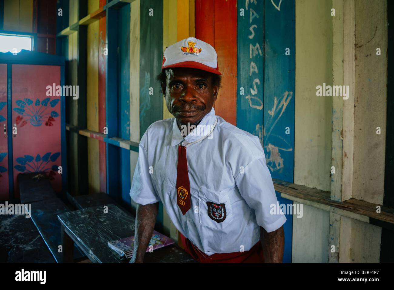 Ein erwachsener indigener Papua-Mann in Grundschuluniform in einem Klassenzimmer Stockfoto