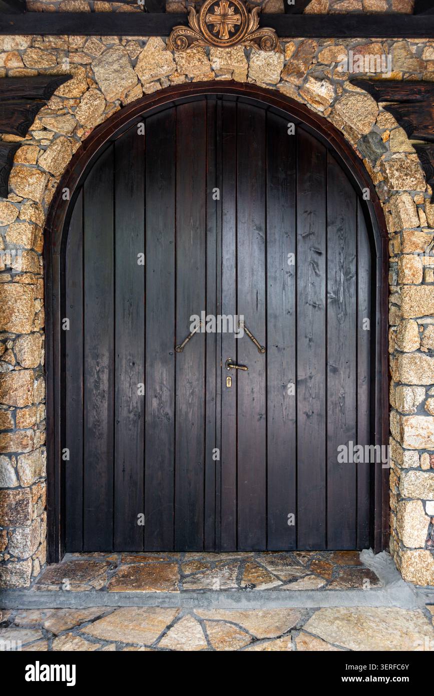 Rustikale Holzbogentür in Steinmauer Stockfoto