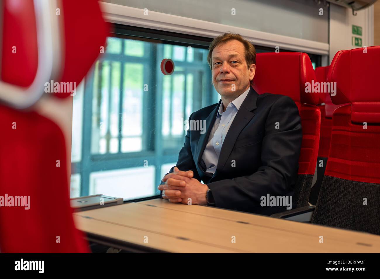 Mann mittleren Alters sitzt an einem Tisch in einem modernen Wagen Stockfoto