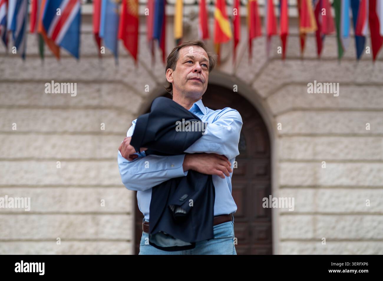 Mann mit Jacke vor dem Gebäude mit Fahnen. Stockfoto