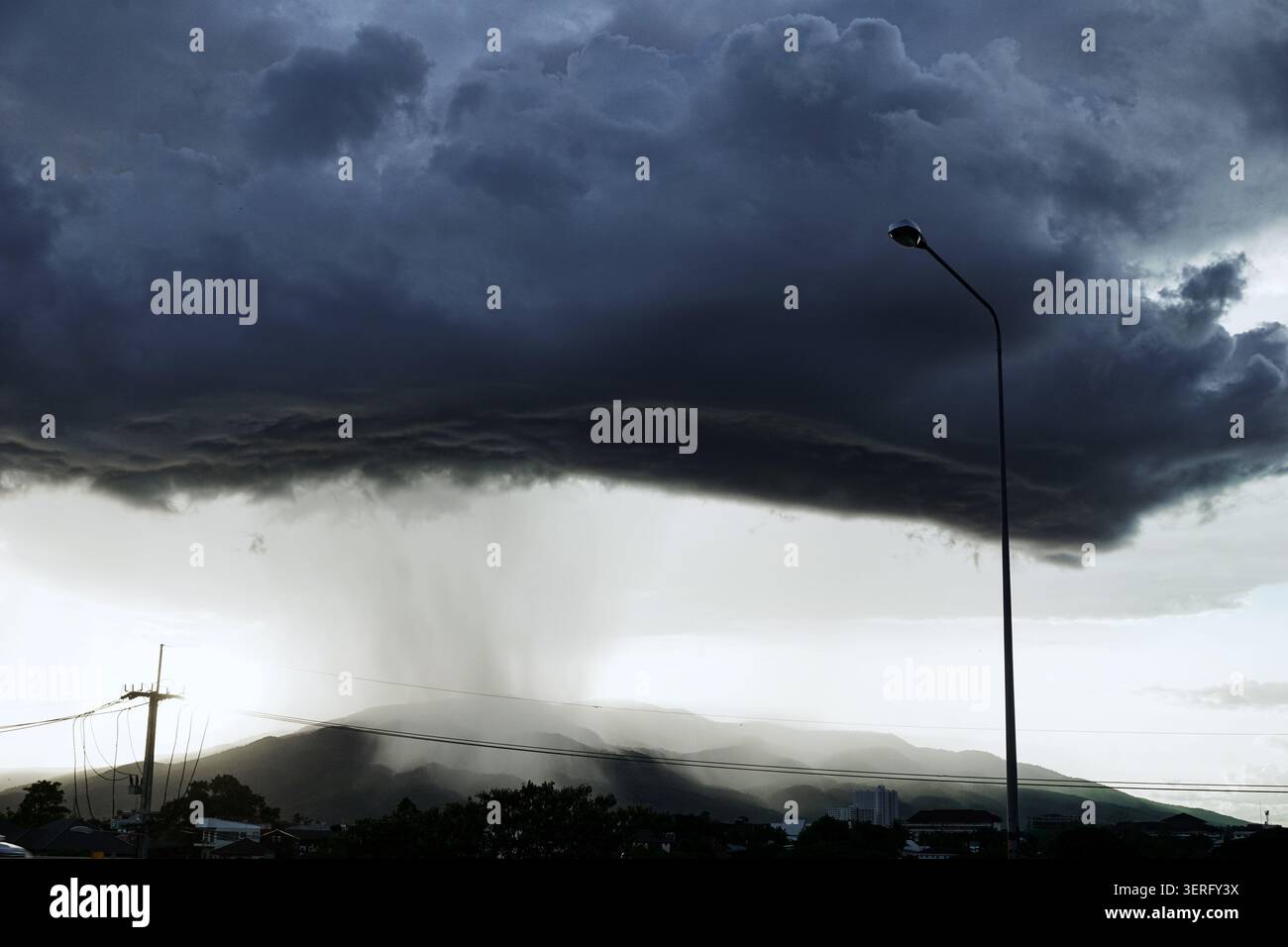 Starke Arkuswolkenbildung mit sichtbarem Regenschacht, der auf Berge fällt Stockfoto