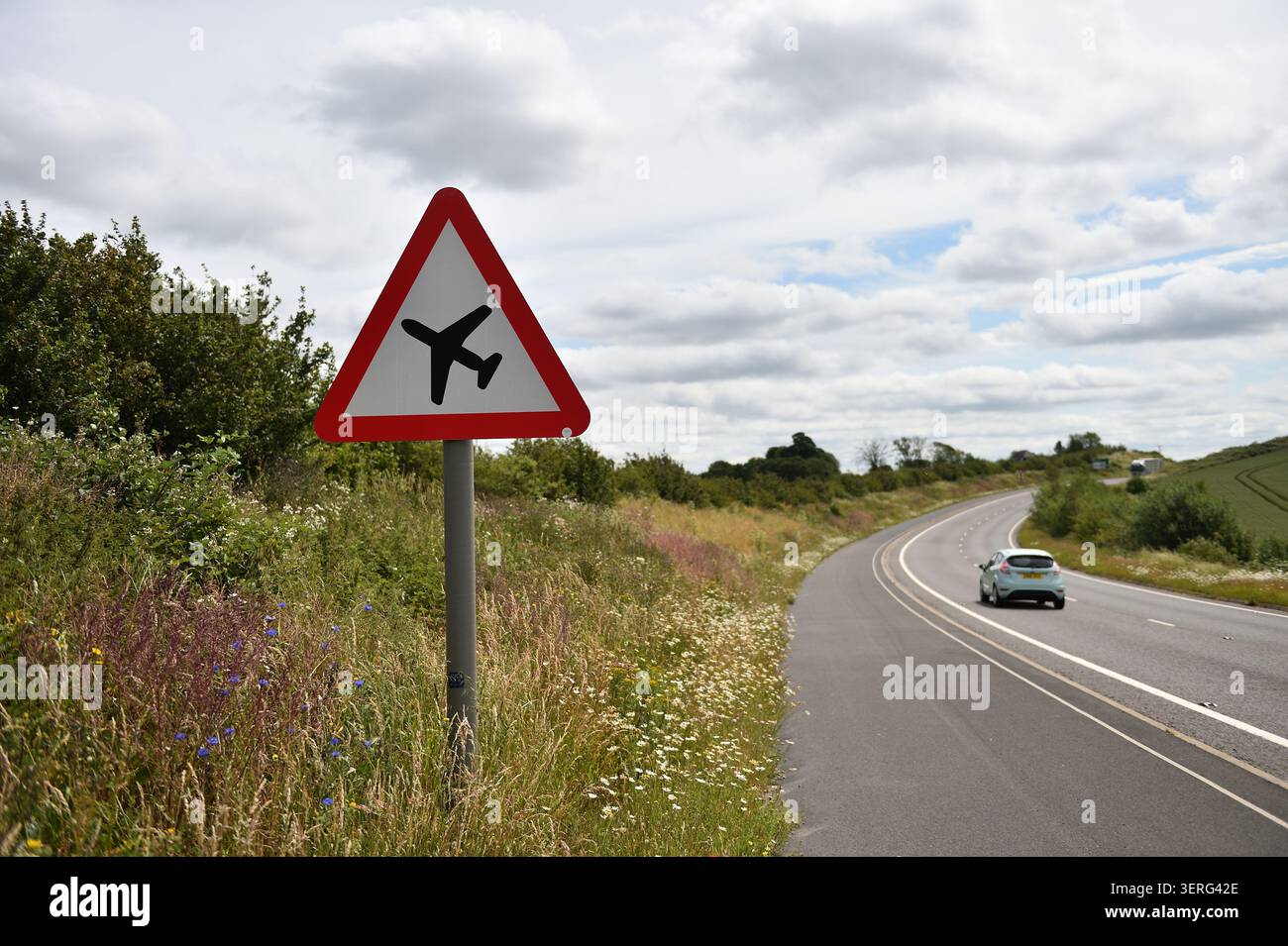 Warnung Straßenschild am Grasrand für tief fliegende Flugzeuge, Grasbänke durften lange wachsen für die Natur und Wildblumen A6 Leicestershire, großbritannien. Stockfoto