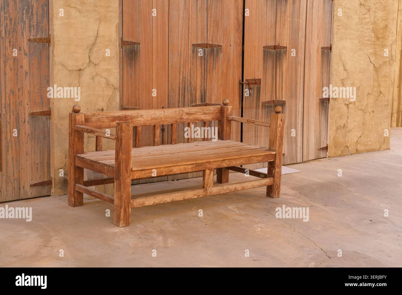 Traditionelle Holzbank neben dem historischen arabischen Gebäude. Rustikale Möbel und historische Architektur im Nahen Osten Stockfoto
