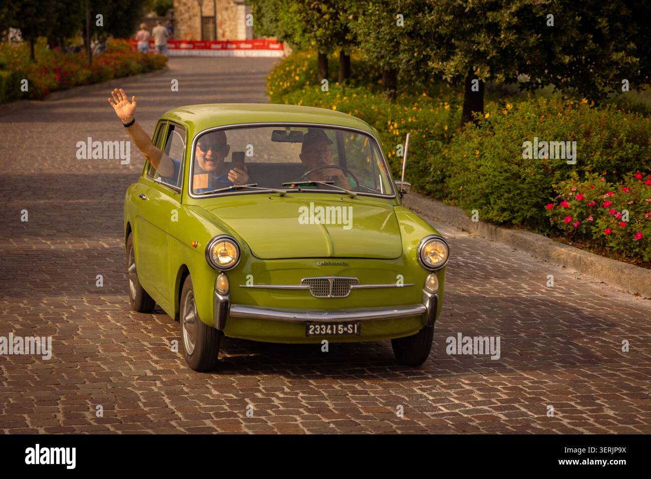 Vintage Autobianchi Bianchina fährt 1000 durch Sirmione während des historischen Motorenevent Miglia am Gardasee, Italien, mit lächelnden Teilnehmern Stockfoto